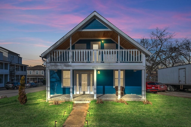 view of front of property featuring a balcony, a yard, and french doors