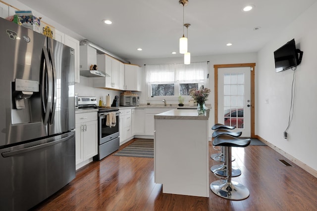 kitchen featuring dark wood-style flooring, visible vents, appliances with stainless steel finishes, white cabinets, and a kitchen breakfast bar