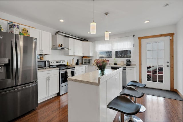 kitchen with stainless steel appliances, light countertops, wall chimney range hood, and white cabinetry