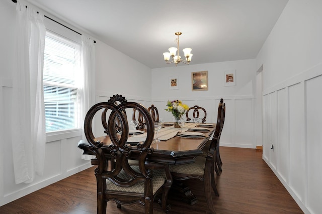 dining room featuring a notable chandelier, a decorative wall, dark wood-type flooring, and wainscoting