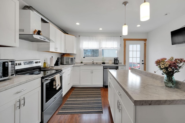 kitchen with appliances with stainless steel finishes, wall chimney exhaust hood, white cabinets, and dark wood-type flooring