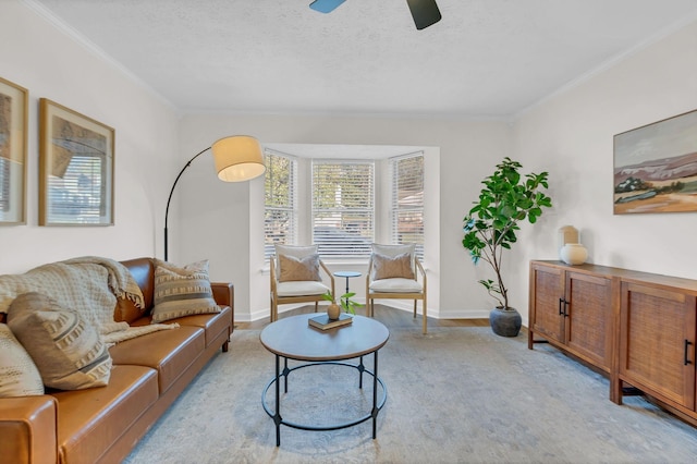 living room featuring light wood finished floors, a textured ceiling, baseboards, and crown molding