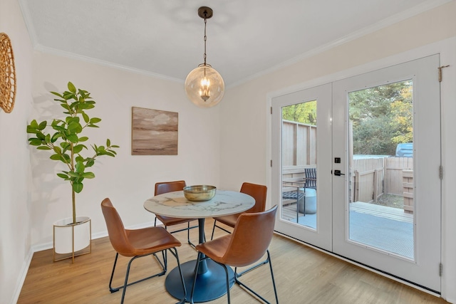 dining area featuring light wood-style floors, baseboards, crown molding, and french doors