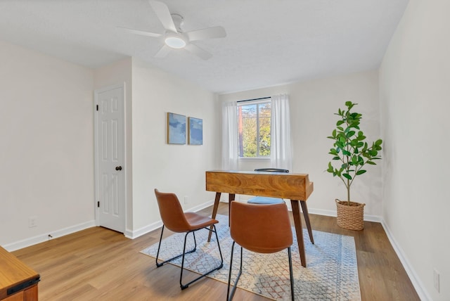 dining room with wood finished floors, a ceiling fan, and baseboards