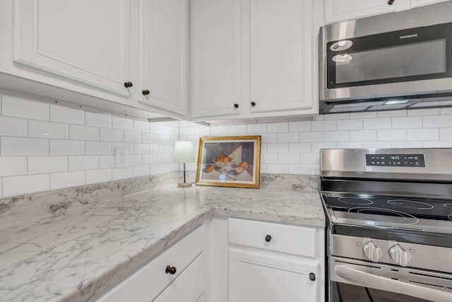 kitchen featuring light stone countertops, white cabinetry, appliances with stainless steel finishes, and decorative backsplash