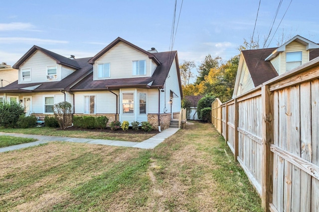 view of side of home featuring fence private yard, brick siding, and a yard