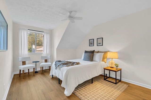 bedroom featuring a ceiling fan, a textured ceiling, baseboards, and wood finished floors