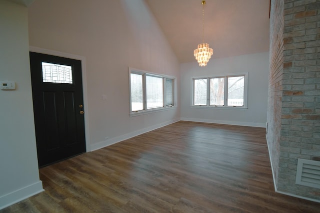 entryway featuring a chandelier, high vaulted ceiling, dark wood-type flooring, and baseboards