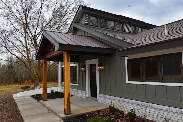 exterior space with brick siding, board and batten siding, a standing seam roof, a patio area, and metal roof