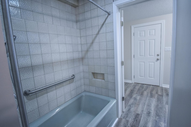 bathroom with shower / washtub combination, baseboards, and wood finished floors