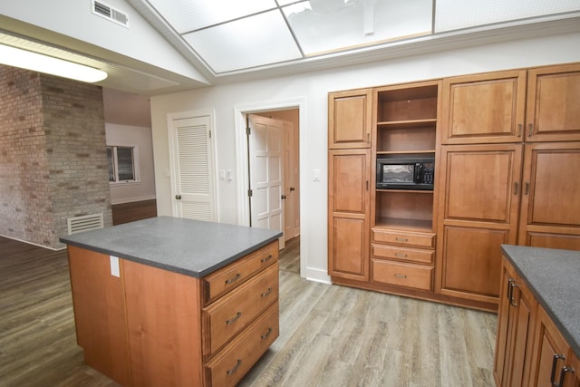 kitchen featuring brown cabinets, dark countertops, and visible vents