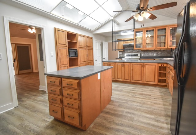 kitchen with brown cabinets, open shelves, dark countertops, light wood-style floors, and black appliances