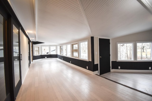 empty room with lofted ceiling, wood-type flooring, and baseboards