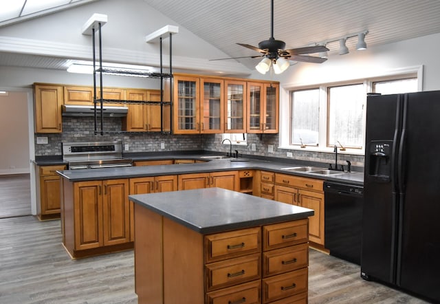 kitchen featuring a center island, brown cabinetry, a sink, ventilation hood, and black appliances