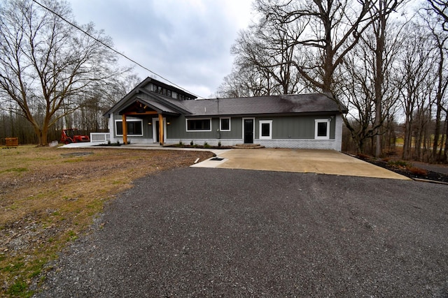 view of front of house with covered porch, driveway, and brick siding