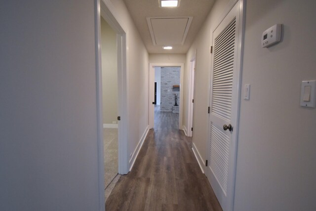 hall with attic access, baseboards, and wood finished floors