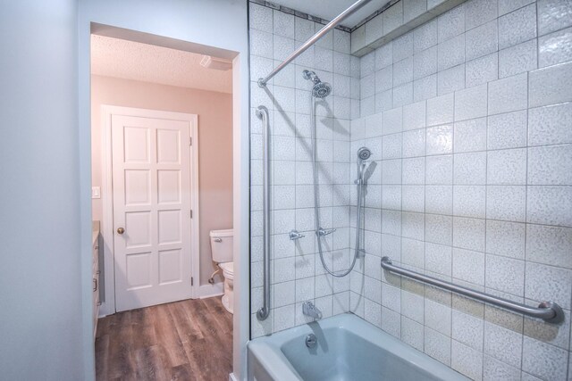 bathroom featuring a textured ceiling, shower / bathing tub combination, wood finished floors, and toilet