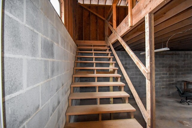 staircase featuring concrete flooring and concrete block wall