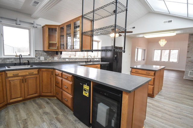 kitchen featuring wine cooler, freestanding refrigerator, brown cabinets, and a sink