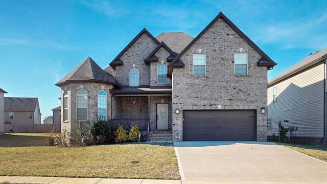 french country style house with brick siding, a shingled roof, an attached garage, a front yard, and driveway