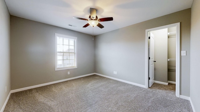 carpeted empty room featuring visible vents, ceiling fan, and baseboards