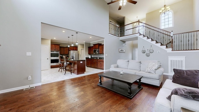 living area with a high ceiling, light wood finished floors, stairs, and baseboards