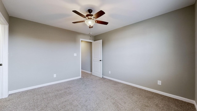 carpeted empty room featuring ceiling fan and baseboards