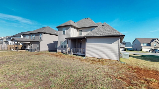 back of house featuring a residential view, roof with shingles, a yard, and central AC unit