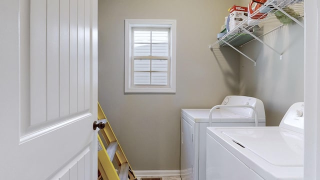 laundry room with laundry area, washing machine and clothes dryer, and baseboards