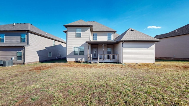 rear view of property with a yard, central AC unit, a porch, and a shingled roof