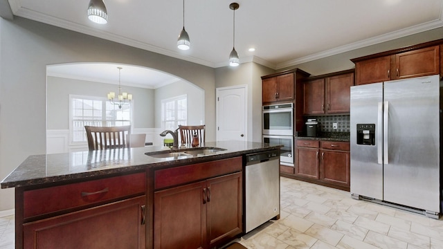 kitchen featuring decorative backsplash, appliances with stainless steel finishes, dark stone countertops, hanging light fixtures, and a sink