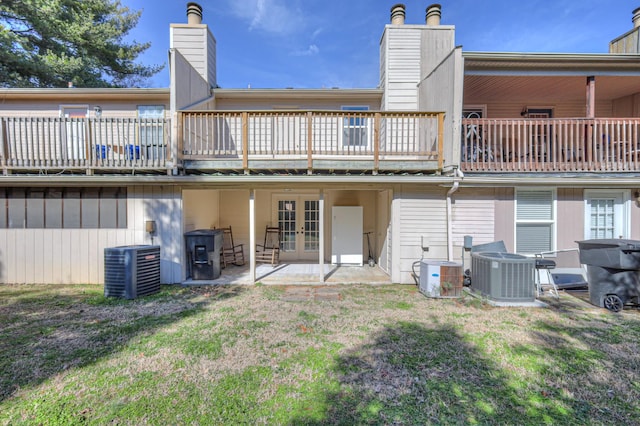 rear view of house with a yard, a chimney, central AC, and french doors
