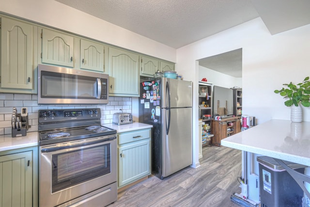 kitchen featuring appliances with stainless steel finishes, light countertops, backsplash, and light wood finished floors