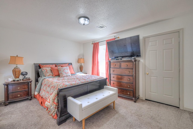 bedroom with a textured ceiling, carpet, and visible vents