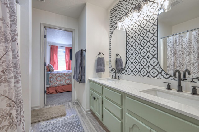 bathroom featuring double vanity, wood finished floors, a sink, and visible vents