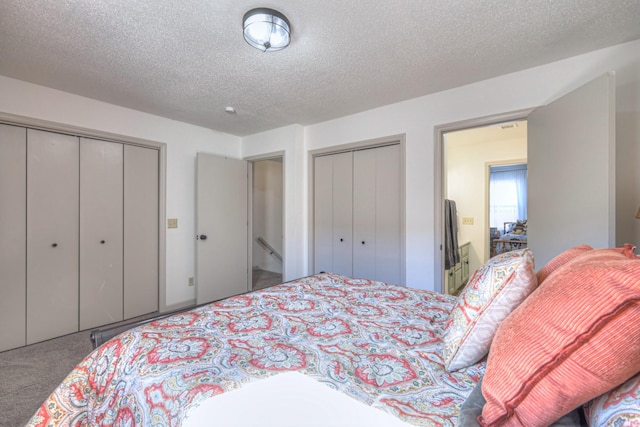 carpeted bedroom featuring a textured ceiling and two closets