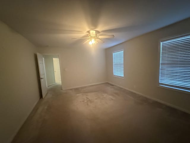 empty room with ceiling fan, baseboards, and light colored carpet