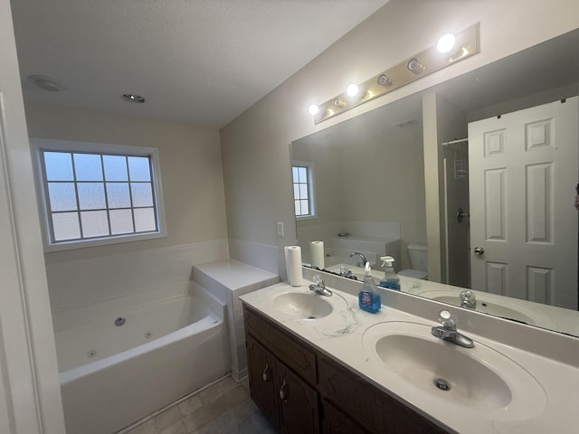 full bathroom with a whirlpool tub, a textured ceiling, and a sink