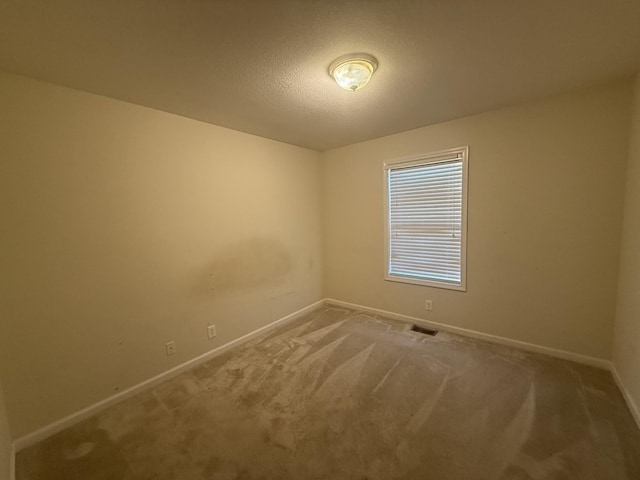 carpeted empty room with a textured ceiling and baseboards