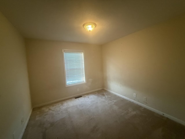 carpeted spare room featuring visible vents and baseboards