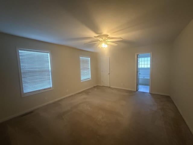 carpeted empty room featuring ceiling fan, visible vents, and baseboards