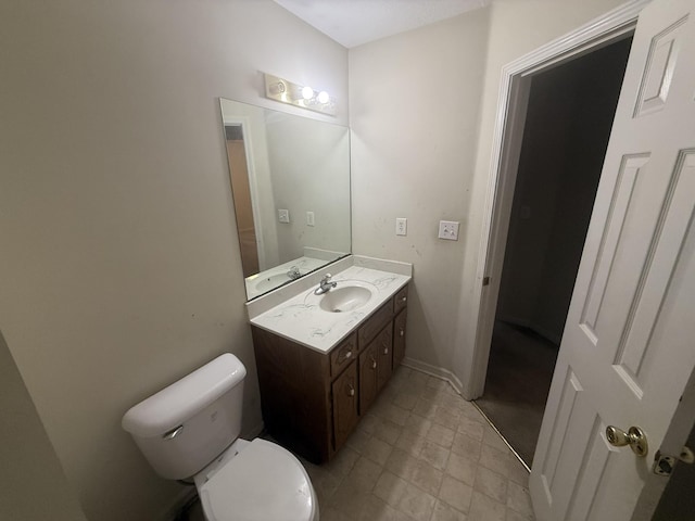 bathroom featuring toilet, vanity, and baseboards