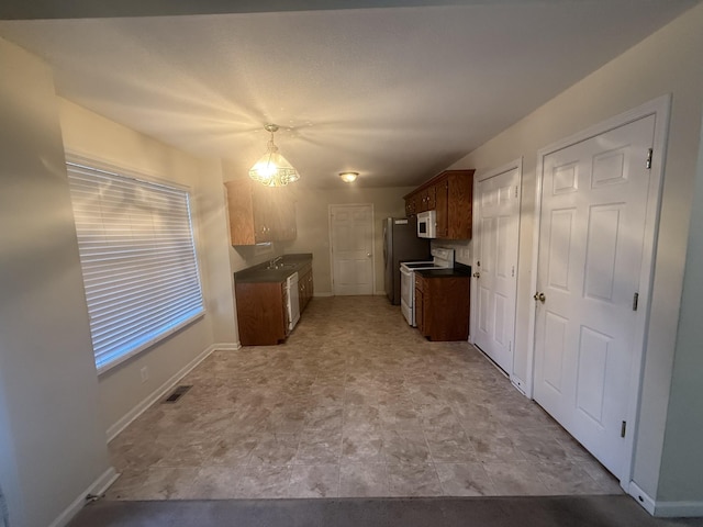 kitchen featuring white appliances, dark countertops, visible vents, and baseboards