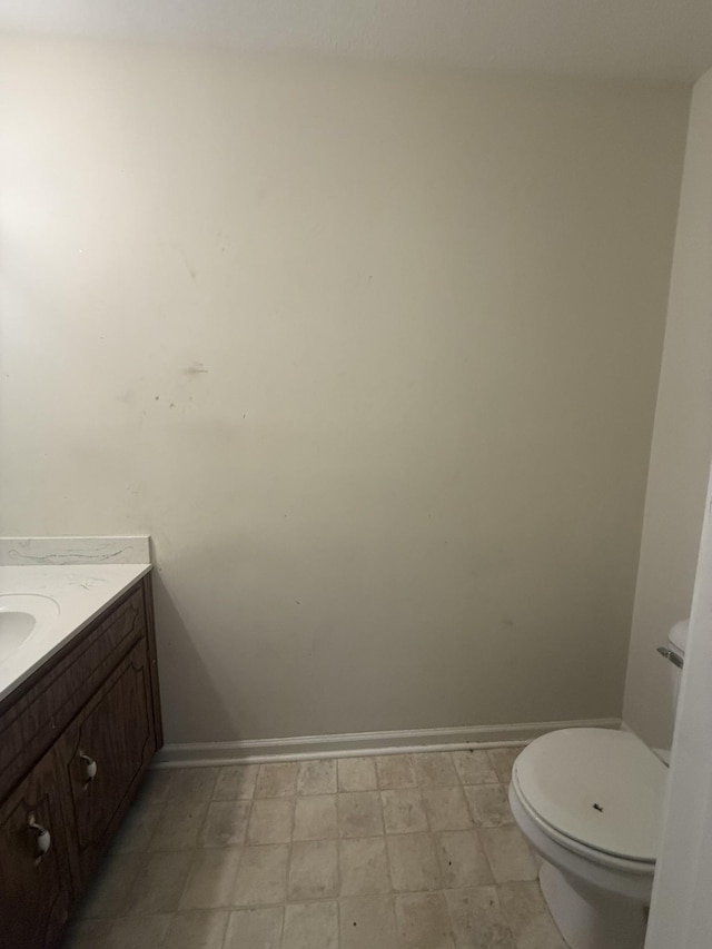 bathroom featuring toilet, tile patterned floors, baseboards, and vanity