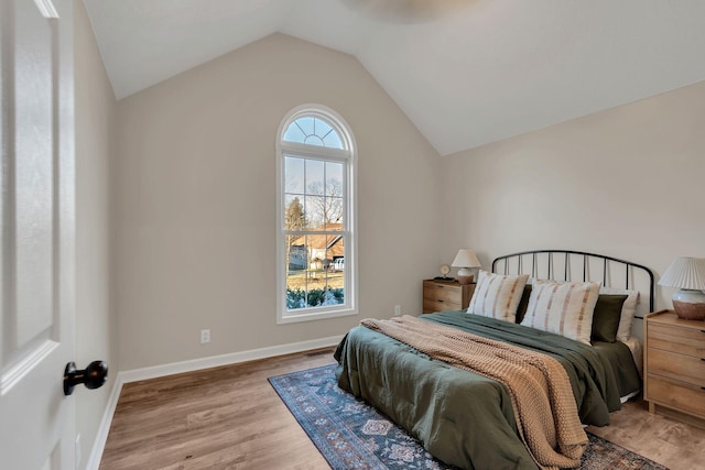 bedroom featuring baseboards, vaulted ceiling, and wood finished floors