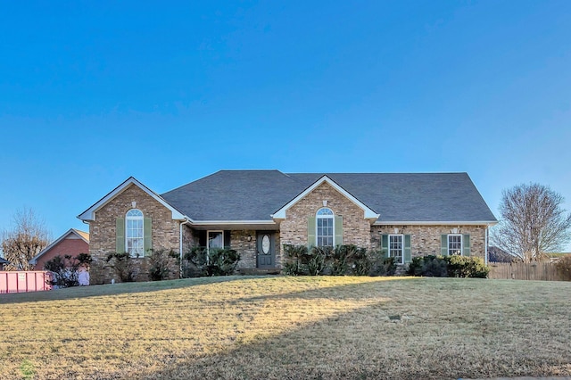 ranch-style home with brick siding, fence, and a front yard