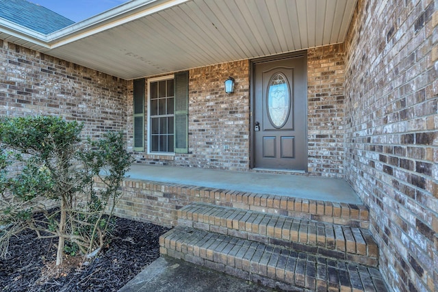 entrance to property with covered porch and brick siding