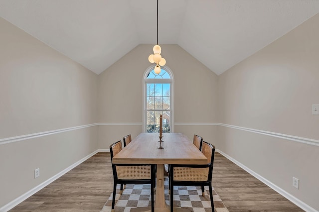 dining area with lofted ceiling, baseboards, and wood finished floors