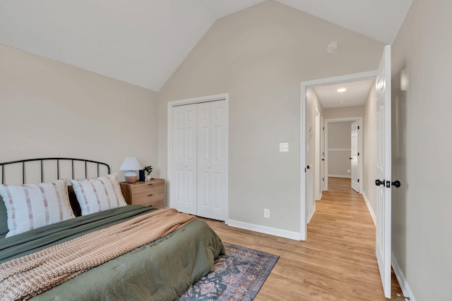 bedroom with high vaulted ceiling, light wood-style floors, baseboards, and a closet