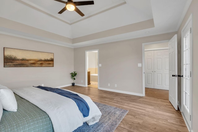 bedroom featuring baseboards, a raised ceiling, connected bathroom, ceiling fan, and wood finished floors